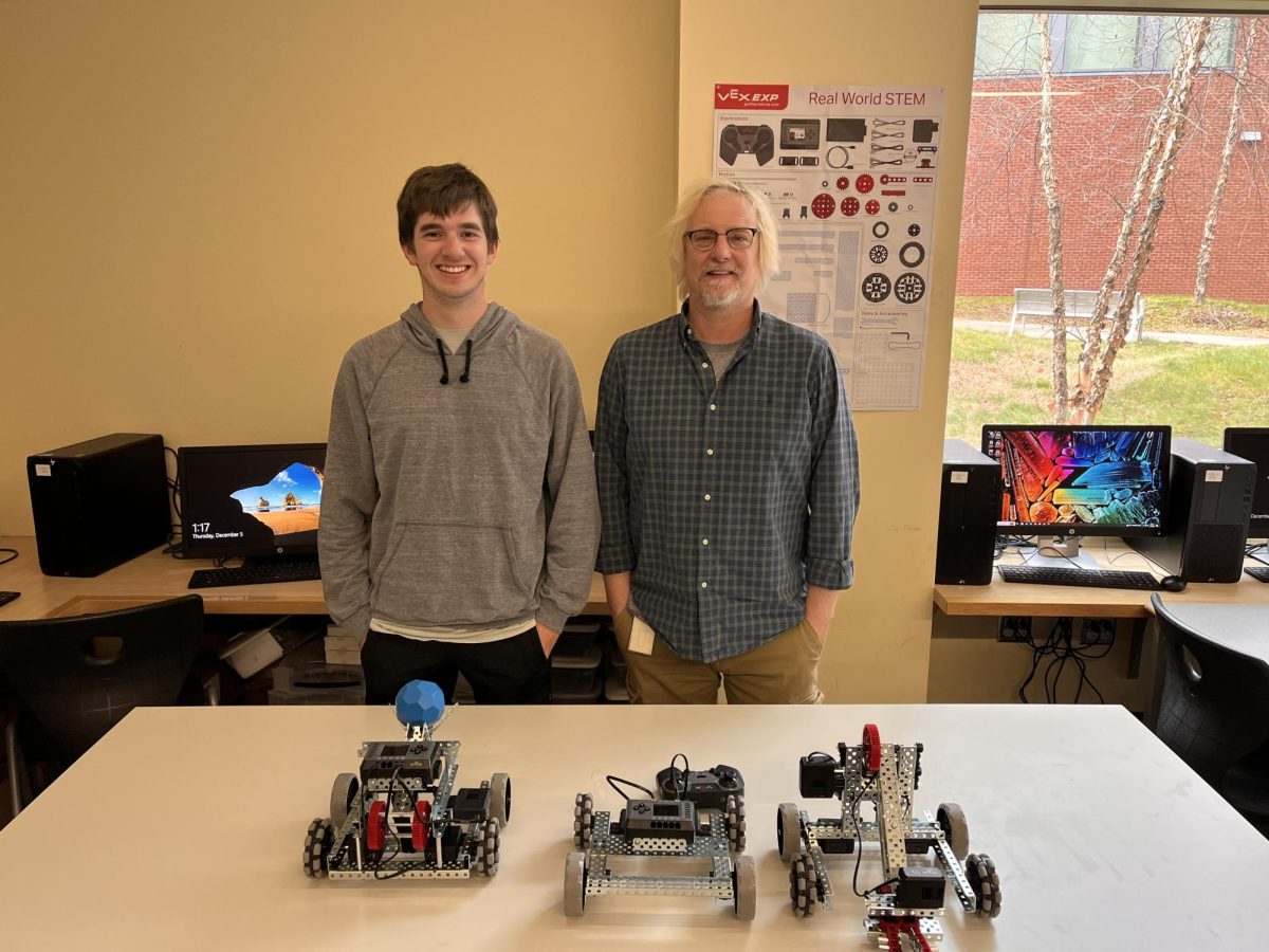 Ryan Gray, Senior, and Mr. Madura, standing behind robots created in the tech club