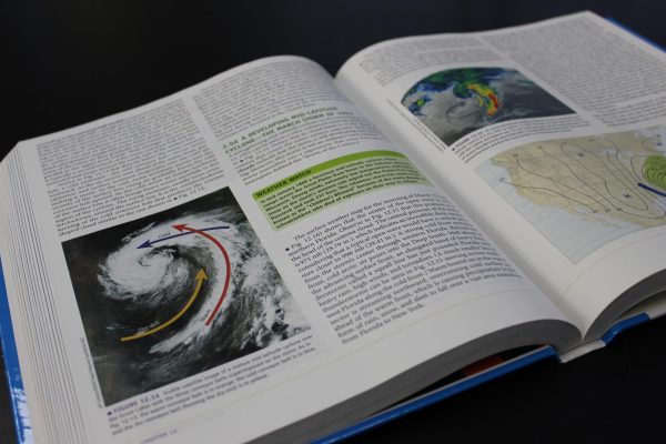 A photo of a meteorology textbook, showcasing storm systems like hurricanes.