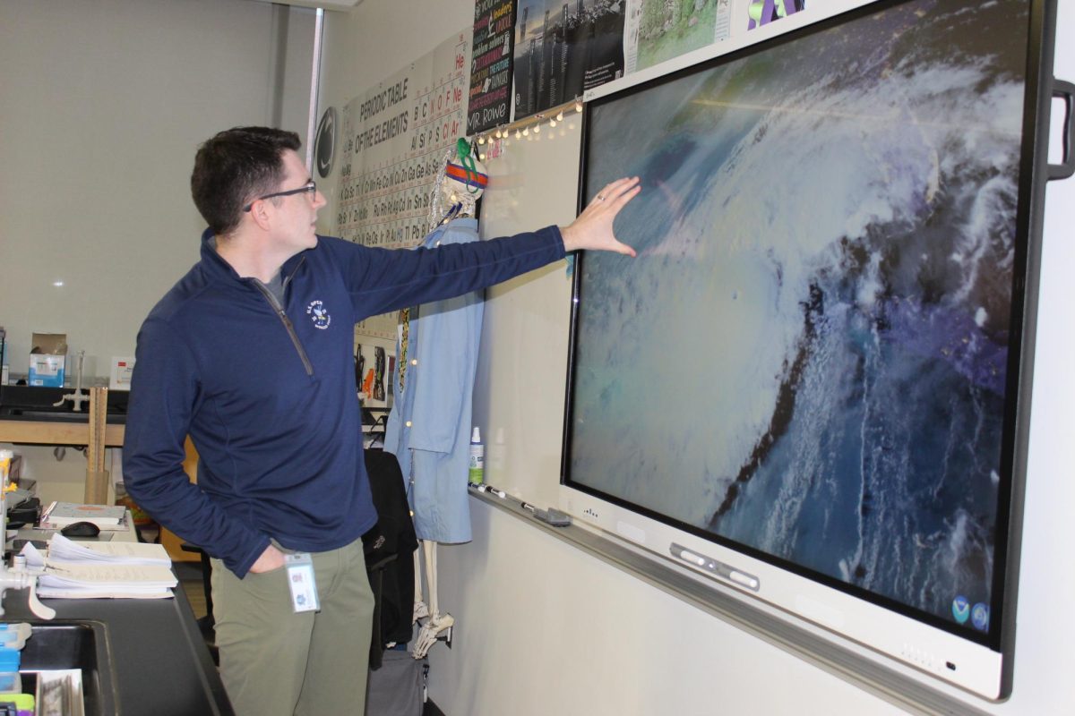 Mr. Rowe standing in front of a smart board, presenting and explaining a hurricane system.