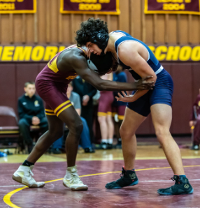 Pedro Reis wrestling someone from Milford High School in the Milford gymnasium